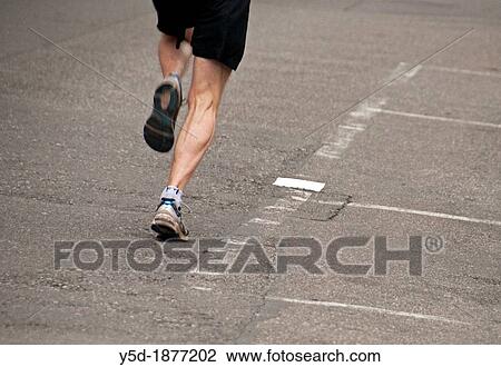 Stock Image - one man jogging on the street, legs only, Geneva, Switzerland. Fotosearch