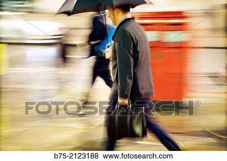 one unrecognizable executive with portfolio walking hurriedly under an umbrella in the street raining, in London, England, UK, Europe View Large Photo Image Stock Photo - one unrecognizable executive with portfolio walking hurriedly under an umbrella in the street raining, in London, England, UK, Europe. Fotosearch