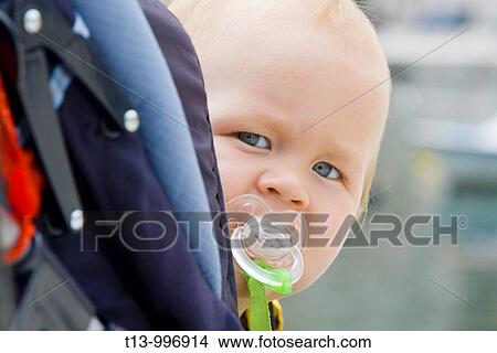 One year old baby boy looking over shoulder with teat in mouth View Large Photo Image Picture - One year old baby boy looking over shoulder with teat in mouth. Fotosearch