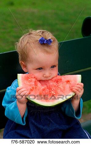 Stock Image - One year old baby girl eating watermelon.. Fotosearch