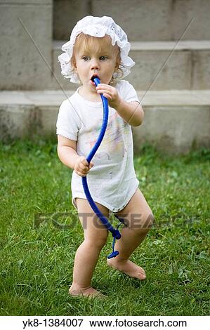 One Year Old Baby Girl Standing Outside and Blowing into Tube View Large Photo Image Stock Photo - One Year Old Baby Girl Standing Outside and Blowing into Tube. Fotosearch