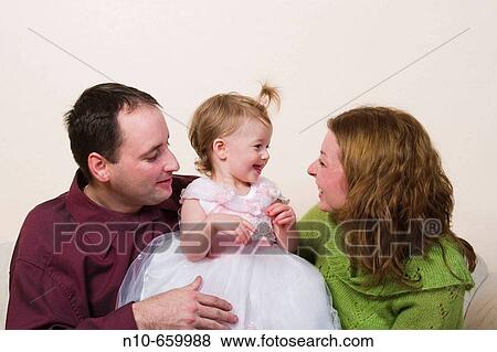 One year old blond girl, in her birthday dress, and her parents, sitting on a sofa. View Large Photo Image Stock Photo - One year old blond girl, in her birthday dress, and her parents, sitting on a sofa.. Fotosearch