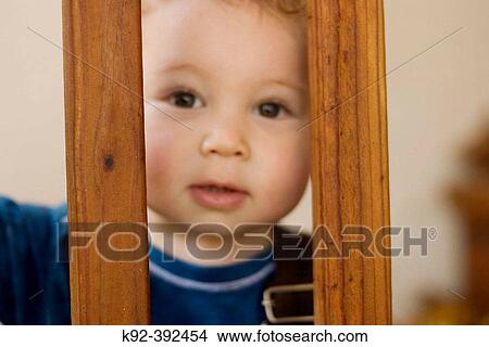 One year old boy looking through the railing of outdoor stairs View Large Photo Image Picture - One year old boy looking through the railing of outdoor stairs. Fotosearch
