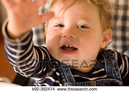 Picture - one year old boy sitting in his high chair.. Fotosearch