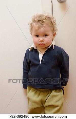 Stock Image - One year old boy standing in front of a door. Fotosearch