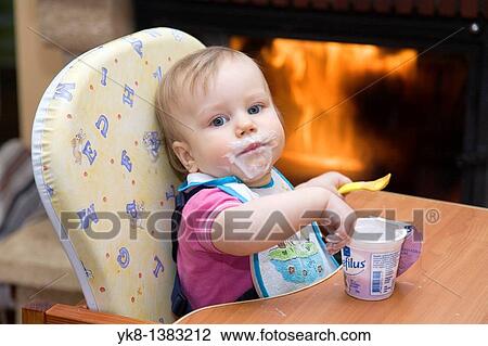 One year old dirty baby girl in high chair eating yogurt using spoon View Large Photo Image Stock Image - One year old dirty baby girl in high chair eating yogurt using spoon. Fotosearch