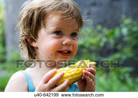 Stock Photo - one year old girl eating corn on the cob. Fotosearch