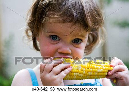 Stock Photo - One year old girl eating corn on the cob.. Fotosearch