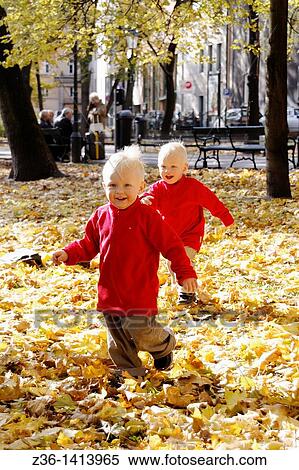 Stock Photography - One year old twin boys having fun at fall. Fotosearch