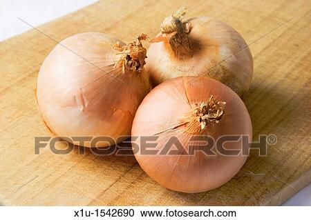 Stock Image - Organic Onions on a Chopping Board. Fotosearch