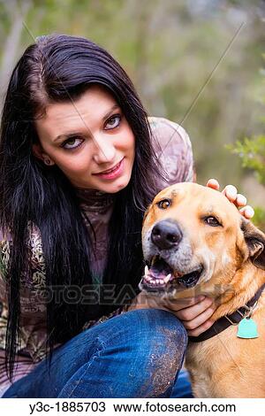 Stock Image - Outdoor portrait of young woman with blackmouth cur dog, Female 18 years old, long black hair, Caucasian, Texas, USA. Fotosearch