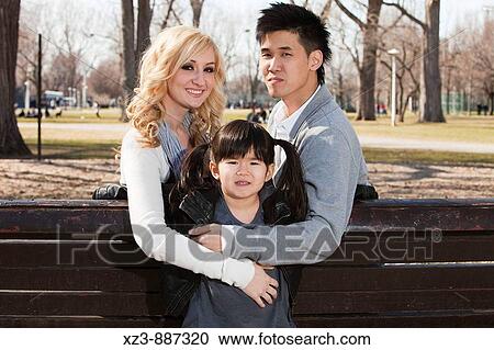 Stock Image - Outdoors portrait of a bi-racial family. Fotosearch