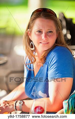 Stock Photo - Outdoot portrait of 45 years old woman sitting relaxed on a table. Fotosearch
