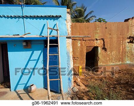 Stock Image - Painted house next to weathered wall in a building that was removed to make way for upcoming highway in Nagasandra, Karnataka, India.. Fotosearch