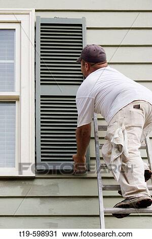 Painter on a ladder holding up a wood shutter to a window of a Victorian house in Swampscott, Massachusetts. USA. View Large Photo Image Stock Image - Painter on a ladder holding up a wood shutter to a window of a Victorian house in Swampscott, Massachusetts. USA.. Fotosearch