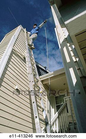 Painter spraying paint on building exterior View Large Photo Image Stock Photograph - Painter spraying paint on building exterior. Fotosearch