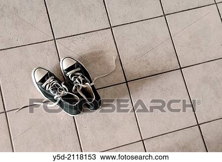 Stock Image - Pair of black sneakers on the tiles.. Fotosearch