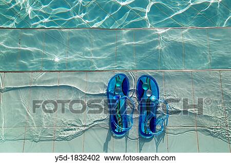 Stock Image - pair of female blue sandals left on the stairs leading to the swimming pool. Fotosearch