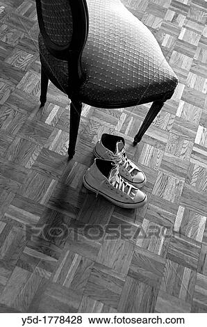 pair of sneakers on the wooden floor next to the old time chair View Large Photo Image Stock Photo - pair of sneakers on the wooden floor next to the old time chair. Fotosearch