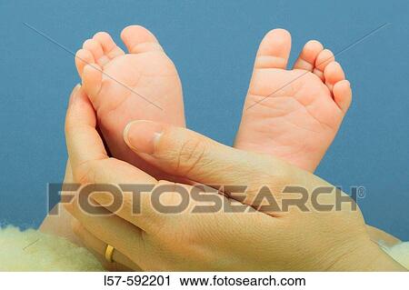 Stock Image - Parent holding baby's feet. Fotosearch