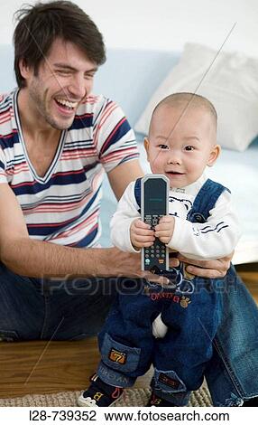 Parents with baby boy (6-11 months) sitting on sofa, smiling View Large Photo Image Stock Image - Parents with baby boy (6-11 months) sitting on sofa, smiling. Fotosearch