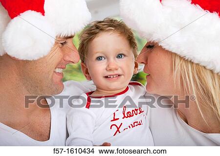 Parents with their one year old son at Christmas time View Large Photo Image Picture - Parents with their one year old son at Christmas time. Fotosearch