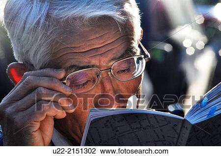 Stock Image - Paris, France, a Japanese tourist reading a guidebook. Fotosearch