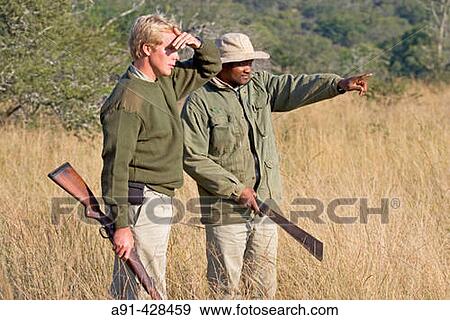 Stock Photo - Park Rangers Ryan Kewley and Thomas Nsele. Game drive in the Phinda private park. Kwazulu-Natal province. South Africa. Fotosearch
