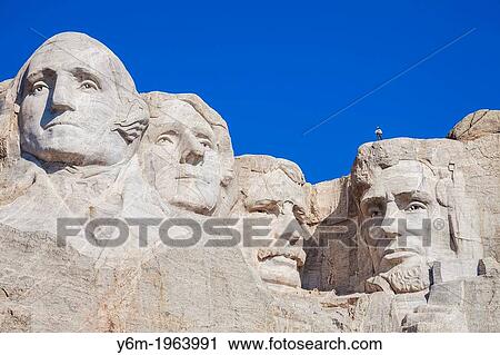 Stock Image - Park service employee standing on Lincolns head while preparing to rappel down the face of Mount Rushmore as part of a survey group, Mount Rushmore, South Dakota.. Fotosearch
