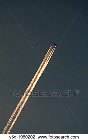 Passenger jet liner flying at high altitude leaving illuminated vapour trails against a dark sky View Large Photo Image Stock Image - Passenger jet liner flying at high altitude leaving illuminated vapour trails against a dark sky. Fotosearch