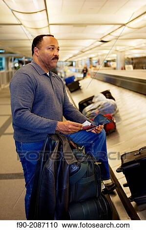 Passenger picks up luggage at airport carousel, Denver, Colorado View Large Photo Image Stock Image - Passenger picks up luggage at airport carousel, Denver, Colorado. Fotosearch