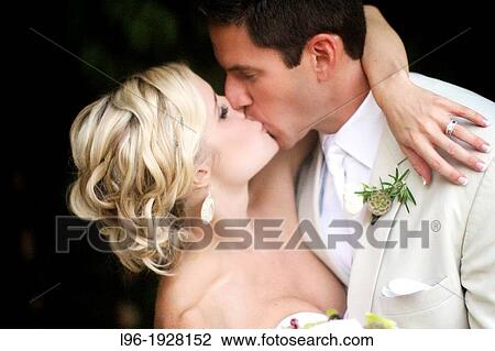 Stock Image - passionate kiss of a new bride and groom @ their garden wedding. Fotosearch