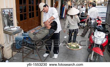 Stock Image - Pavement barber shaves man in chair sidewalk Hanoi Vietnam. Fotosearch