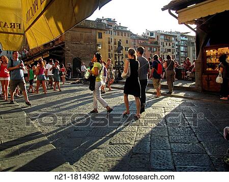 Stock Image - Pedestrians crossing the Ponte Vecchio, a medieval bridge over the Arno River Florence, Tuscany, Italy, Europe.. Fotosearch