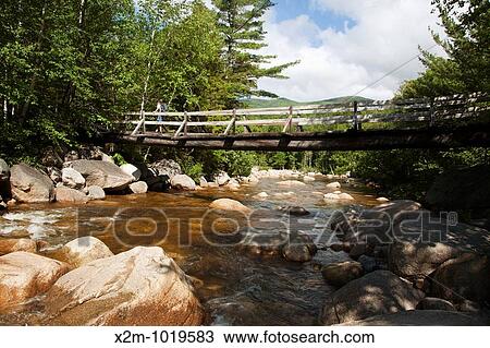 Pemigewasset Wilderness - A hiker on foot bridge which crosses over the Pemigewasset River on Thoreau Falls Trail Located in Lincoln, New Hampshire USA View Large Photo Image Stock Image - Pemigewasset Wilderness - A hiker on foot bridge which crosses over the Pemigewasset River on Thoreau Falls Trail Located in Lincoln, New Hampshire USA. Fotosearch