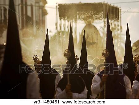 Stock Image - Penitents walk in front of a throne displaying a sculpture of Our Lady of Sorrows during an Easter Holy Week procession in Carmona village, Seville province, Andalusia, Spain, April 20, 2011. Fotosearch