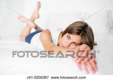 Stock Photo - Pensive young woman lying in bed. Fotosearch