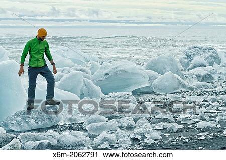 Stock Image - People and ice blocks in Jokulsarlon sand beach. Vatnajokull National Park. Iceland, Europe.. Fotosearch