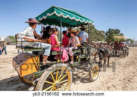 Stock Image - People Being Transported In A Traditional Wagon, El Rocio Festival, El Rocio, Andalusia, Spain.. Fotosearch
