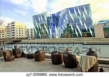 Stock Photography - People have a rest on the canal embankment of the modern district of Copenhagen Denmark.. Fotosearch