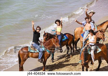 Picture - People horseback riding at the beach. Fotosearch