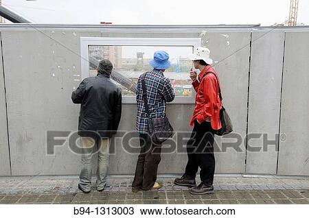 Stock Image - People looking at construction site, Pla? a de les Glories, Barcelona, Catalonia, Spain. Fotosearch