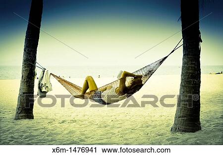 Stock Image - people resting on a hammock Cua Dai beach Hoi An, Vietnam, Asia. Fotosearch