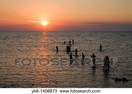 Stock Image - People Silhouettes in Water Against Sun. Fotosearch