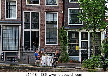 Stock Photograph - People sitting at outdoors oh theirs house, Amsterdam, Holland. Fotosearch