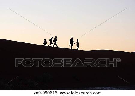 People walking in the sand dune at sunrise, Namib-Naukluft National Park, Namib desert, Namibia View Large Photo Image Stock Photograph - People walking in the sand dune at sunrise, Namib-Naukluft National Park, Namib desert, Namibia. Fotosearch