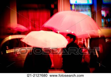 Stock Image - People with umbrellas. Rainy day, night. Barcelona, Catalonia, Spain.. Fotosearch