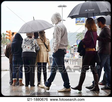 Stock Photograph - People with umbrellas waiting for a traffic light. Barcelona, Catalonia, Spain.. Fotosearch
