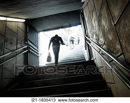 Stock Image - Person coming out of the metro, upstairs, carrying a bag in his hand. Barcelona, Catalonia, Spain.. Fotosearch