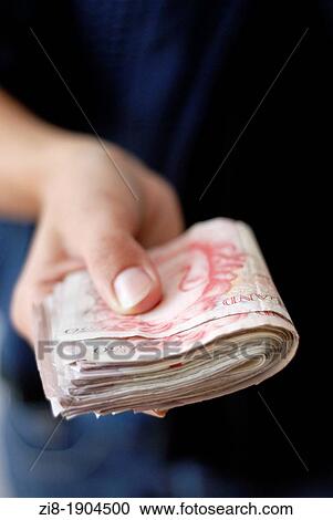 Stock Image - Person handing cash- UK Pound Sterling. Fotosearch